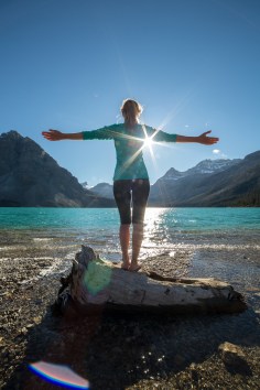 Young woman arms outstretched by the lake embracing life